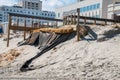 Erosion of the sand of the beach with destruction of a asphalt path after a hurricane and storm. There are large buildings in the