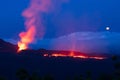 Errupting volcano in moonlit blue nightsky