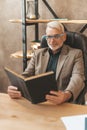 Erudite with a book. A mature student reads an encyclopedia, learning in old age. Professor in the library