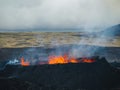 Erupting volcano, lava pouring out into a devastated surrounding, drone shot