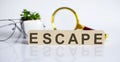 ESCAPE concep on wooden cubes and flower ,glasses ,coins and magnifier on white background