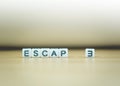 ESCAPE word written in cube on wooden floor on white background