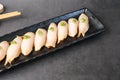 Escolar, oilfish, butterfish nigiri, or sashimi with fresh wasabi on a black plate. Traditional Japanese food