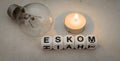 Eskom, electric light bulb and a small candle Royalty Free Stock Photo