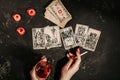 Tarot cards and female hands of fortune teller on black magic table