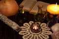 Esoteric still life with burning candle in yellow flame, open old book and crystals. Two green vials and dried sage