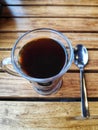 Espresso black tea coffee in a transparent glass cup with a tea spoon on a wooden table high angle shot Royalty Free Stock Photo