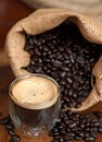 Espresso and Coffee Beans in burlap bag spilling on table Royalty Free Stock Photo