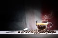 Steaming espresso coffee in glass cup with coffee bens in dark setting. Royalty Free Stock Photo