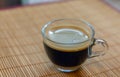 Espresso coffee with golden fine-bubbled crema seen from above in a crystal clear cup on bamboo plate holder. Royalty Free Stock Photo