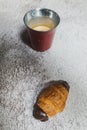 Espresso coffee and tiny chocolate croissant isolated on a rough grey background