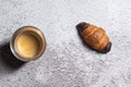 Espresso coffee and tiny chocolate croissant isolated on a rough grey background