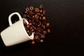 Espresso cup with coffee beans inside fell on the dark textured table Royalty Free Stock Photo