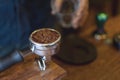 Espresso handle filled with ground coffee. Barista prepares espresso in his coffee shop