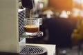 Espresso maker machine breuuing coffee in a glass cup with capsules on white desk at office in the morning Royalty Free Stock Photo