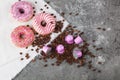 Espresso pink plastic capsules with foil and coffee beans and sweet donuts on gray concrete background