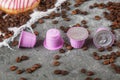 Espresso Pink Plastic Capsules With Foil And Coffee Beans And Sweet Donuts On Gray Concrete Background