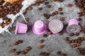 Espresso pink plastic capsules with foil and coffee beans and sweet donuts on gray concrete background