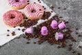 Espresso pink plastic capsules with foil and coffee beans and sweet donuts on gray concrete background