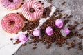 Espresso pink plastic capsules with foil and coffee beans and sweet donuts on gray concrete background