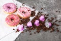 Espresso pink plastic capsules with foil and coffee beans and sweet donuts on gray concrete background