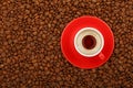Espresso in red cup with saucer on coffee beans Royalty Free Stock Photo
