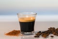 An espresso surrounded by brown sugar and roasted coffee beans on a glass table coffee concept