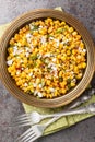 Esquites Mexican Street Corn Salad with jalapeno, cilantro, Cotija cheese, onion and spices close-up on the plate. Vertical top