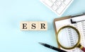 ESR Erythrocyte Sedimentation Rate word on wooden cubes on blue background with chart and keyboard