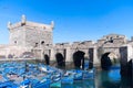 Essaouira citadel, the Scala of the Port in the old town Medina, with iconic blue boats in the harbour and a flock of seagulls.