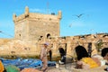 Fishing boats, gear and man with net on background of Castelo Real of Mogador. Royalty Free Stock Photo