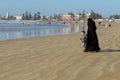 A fully covered Muslim woman walking with her little son on the beach Royalty Free Stock Photo