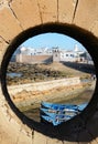 Round window in the fortification of the historical harbour and blue boats