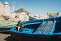 Old senior fisherman on blue wooden boat in Essaouira harbor. Moroccan people.