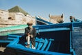 Old senior fisherman on blue wooden boat in Essaouira harbor. Moroccan people.