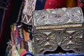 Ornate silver trinket box with colorful textiles on sale in a Moroccan Market