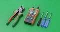 Essential Electrical Tools: Wire Cutters, Power Tester (230V), and Screwdrivers on Green Background Royalty Free Stock Photo