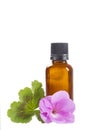 Essential geranium oil in bottle and flowers