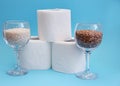 Essential goods for a coronovirus pandemic. rice and buckwheat are in a wine glass instead of wine and toilet paper rolls