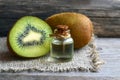 Essential kiwi seed oil in a glass jar with fresh kiwifruit whole and half on old wooden background.Aromatherapy,spa,beauty treatm Royalty Free Stock Photo