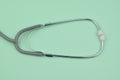 Essential medical stethoscope isolated on a light green paper background