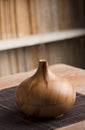 Essential oil air freshener on wood with steam, shelf with books, brown background.