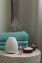 Essential oil aroma diffuser humidifier diffusing water articles in the air. Spa and health care concept. Epsom salt, terry towels Royalty Free Stock Photo