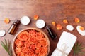 Essential oil bottle, rose flower in bowl, towel and candles on wooden table top view. Spa, aromatherapy, wellness, beauty theme.