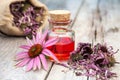 Essential oil and coneflowers on wooden rustic table, bag with h