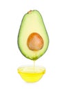 Essential oil dripping from cut avocado into bowl on white background Royalty Free Stock Photo