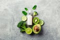 Essential oil dropper bottle with avocado, cucumber, lime, kiwi, broccoli, mint leaves on stone table Royalty Free Stock Photo