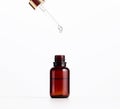 Essential oil falling from the amber glass dropper. Blue bottle of cosmetic oil with a pipette, white background Royalty Free Stock Photo