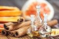 Essential oil in glass bottle with cinnamon sticks and dried red circle slices of citrus fruits orange and lemons on wooden backgr Royalty Free Stock Photo