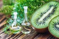 Essential oil in glass bottle with fresh, juicy kiwi fruit and green leaves-beauty treatment. Spa concept. Selective focus.